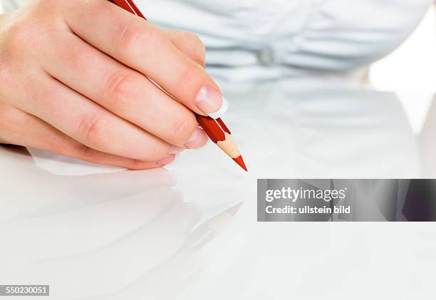 Eine Hand hält einen roten Stift. Symbolfoto für Einsparungen und Budegt Kürzungen.