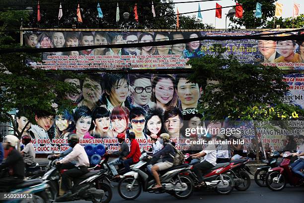 MOTORROLLERFAHRER VOR EINER PLAKATWAND IN DER DIEN BIEN PHU IM DISTRICT 3