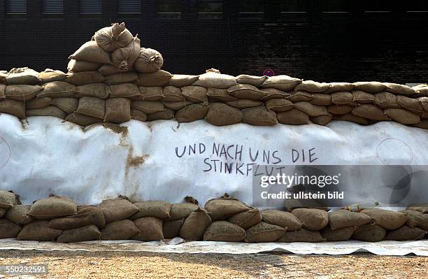 Spöttischer Gruß der Helfer an das kommende Hochwasser auf einem Notdamm aus Sandsäcken in Magdeburg