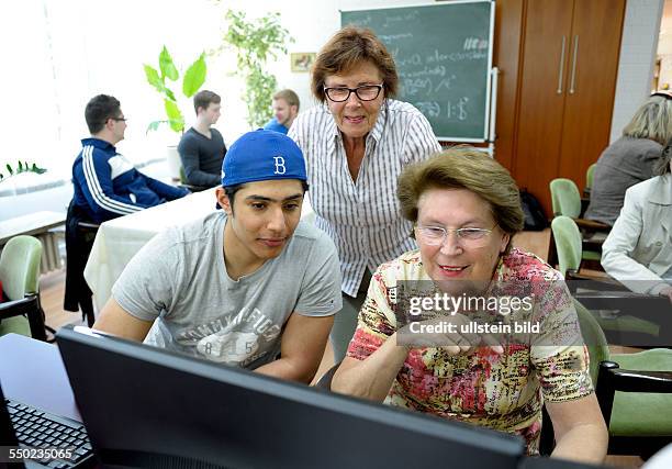 Pupils are teaching seniors how to work with computers in a convention centre in Bonn