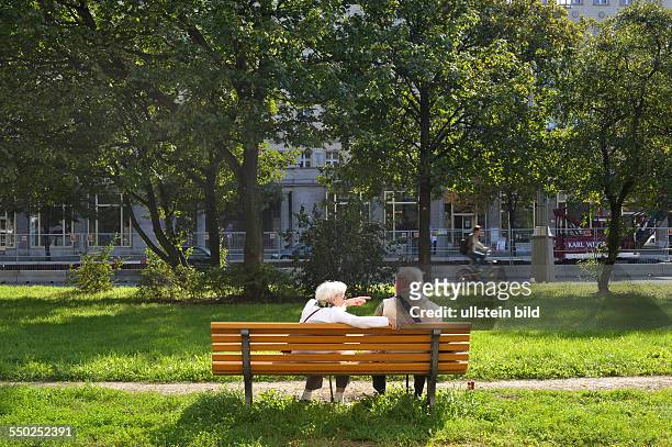 Seniorenpaar unterhält sich auf einer Parkbank an Frankfurter Allee in Berlin-Friedrichshain