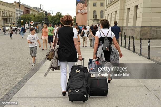 Touristen mit Gepäck auf der Strasse Unter den Linden in Berlin-Mitte