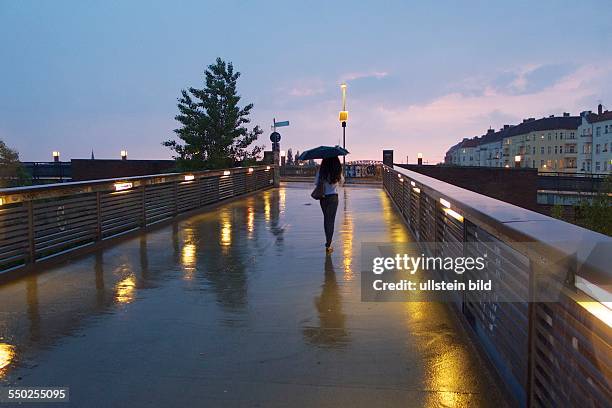 Deutschland, Berlin, abendlicher Schwedter Steg im Regen, Blick zur Behmbruecke, Frau mit Regenschirm