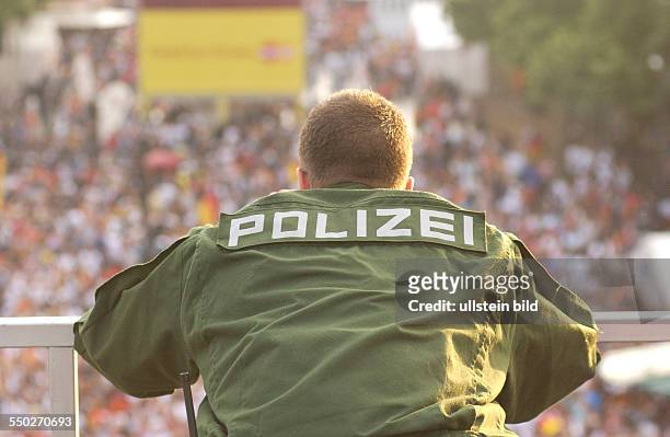 Polizist beobachtet das Fan Fest FIFA-WM 2006 am Brandenburger Tor in Berlin während des Spiels Deutschland-Portugal