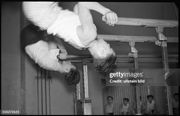 Physical education lesson, boys practising on the parallel bars in the gym