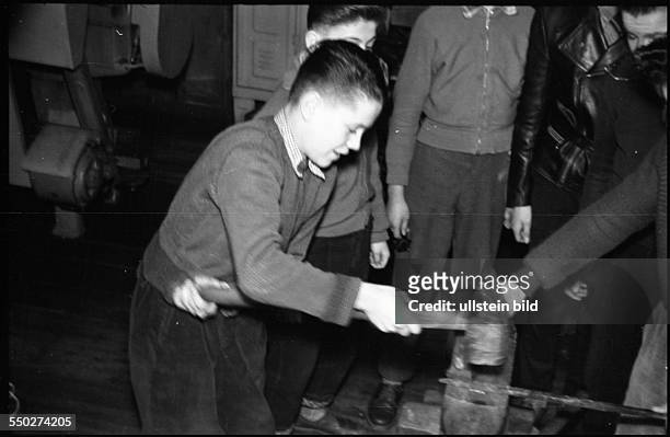 Adolescents working in the metalworking shop, smiting on the anvil