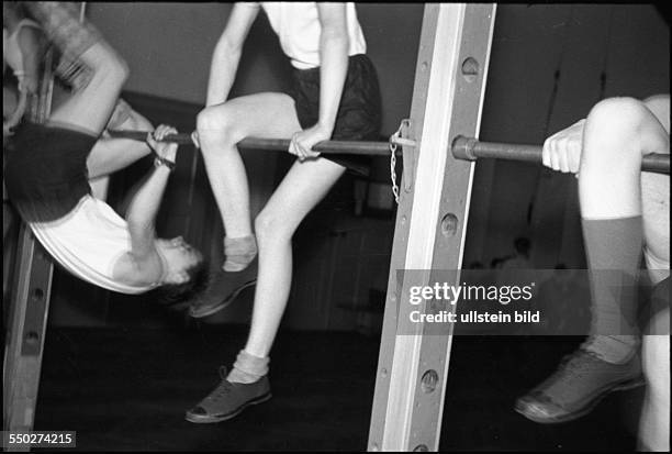 Physical education lesson, boys practising on the horizontal bar in the gym