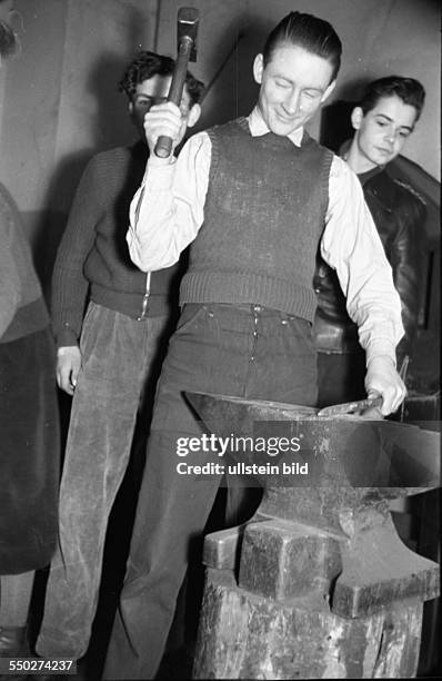 Adolescents working in the metalworking shop, smiting on the anvil