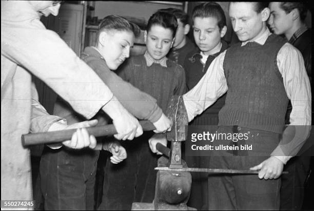 Adolescents working in the metalworking shop, smiting on the anvil