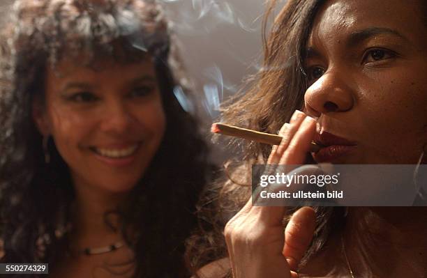 Eine junge Kubanerin raucht genüsslich einen Zigarillo - Präsentation traditioneller Zigarrenherstellung der Dannemann Cigarettenfabrik GmbH in Berlin