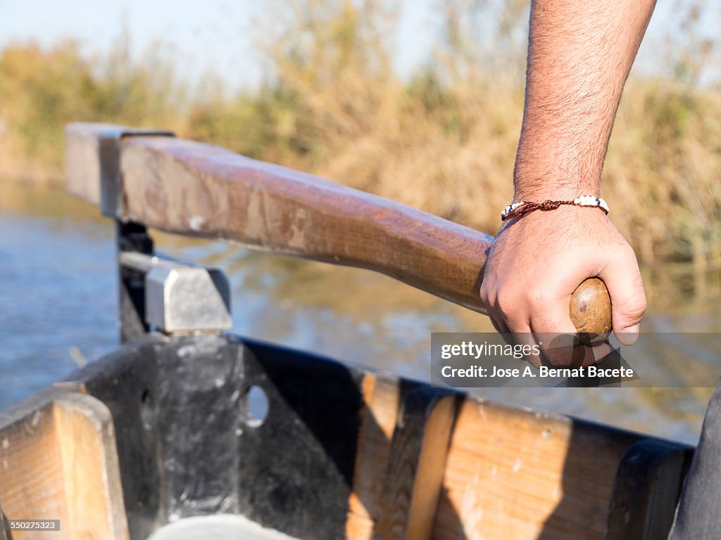Hand of a boatman, grabbing the helm of a boat