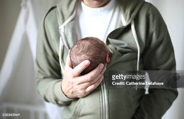 a new born nestled against his dad - dad baby stock-fotos und bilder