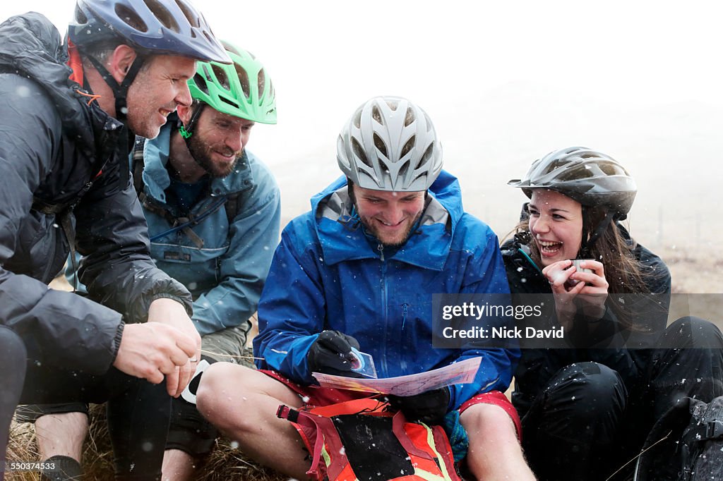 Mountain bikers stop to check their map in the falling snow