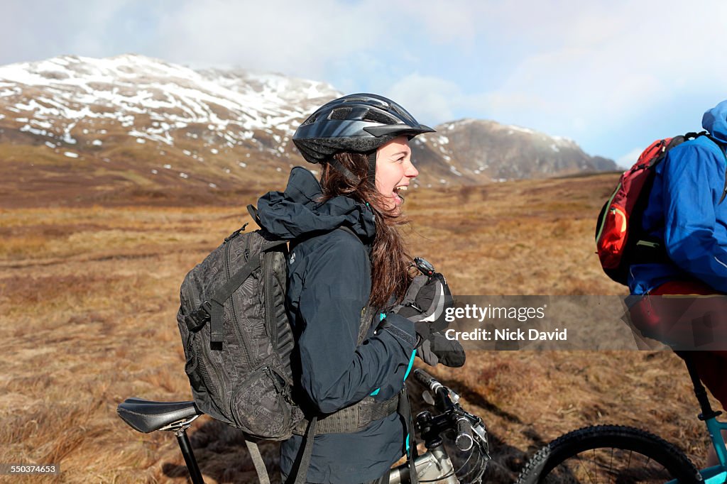 A female mountain biker stops to chat and have a laugh with her friends