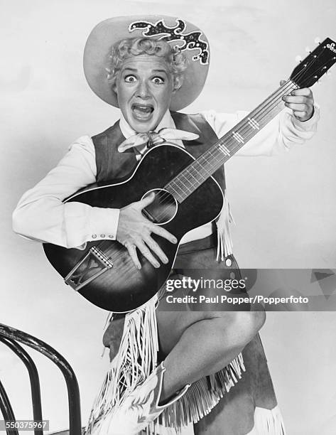 Portrait of American actress and singer, Betty Hutton pictured wearing a cowgirl costume and holding an acoustic guitar, circa 1950.