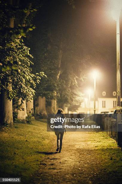 lonely woman walking alone on path - woman capturing city night stockfoto's en -beelden