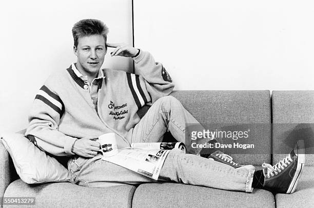 Portrait of BBC Radio 1 disc jockey Simon Mayo sitting on a couch, reading the Christmas edition of the Radio Times and holding a 'Gordon the Gopher'...