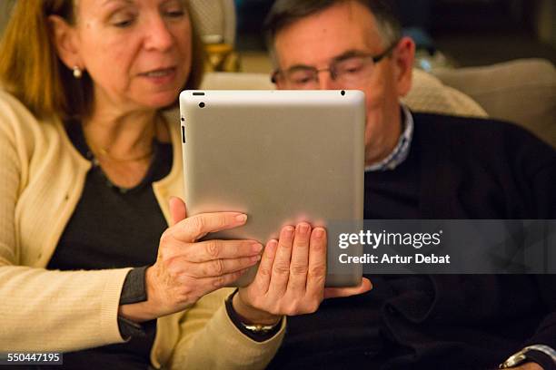 Grandparent couple doing a FaceTime conversation with his granddaughters on iPad tablet.