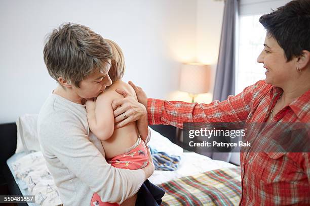 lesbian moms hug their daughter in the bedroom - leaninlgbt stock pictures, royalty-free photos & images