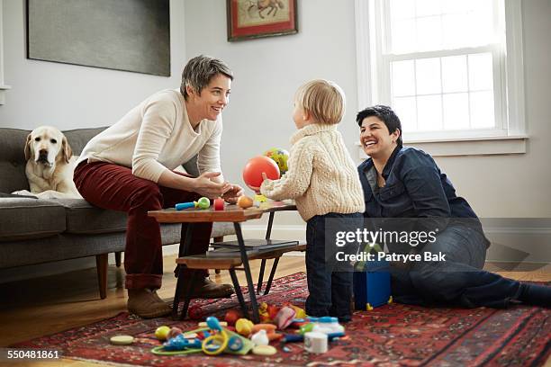 lesbian moms play w/ their daughter in living room - living room young couple stock-fotos und bilder