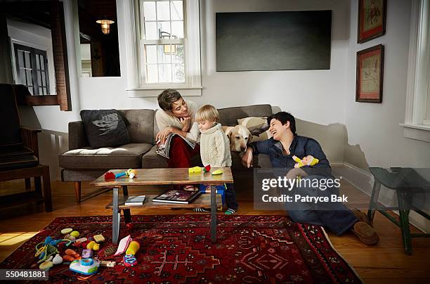 lesbian moms play w/ their daughter in living room - leaninlgbt stock pictures, royalty-free photos & images