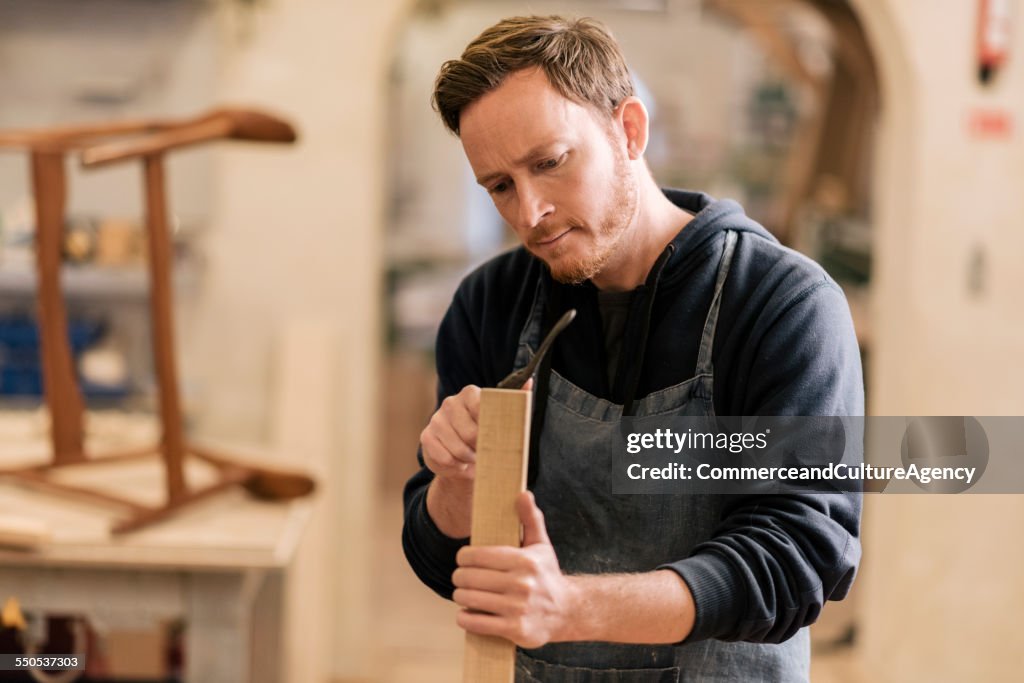 Carpenter in wood workshop working on chair