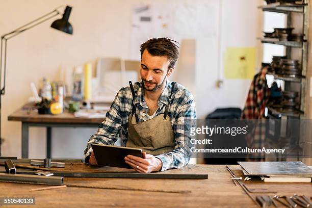 craftsman in metal workshop using tablet - small business stock pictures, royalty-free photos & images