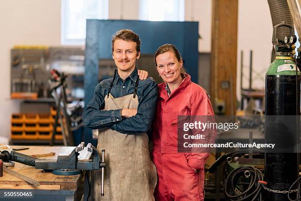 craftswoman and man in metal workshop - red jumpsuit stock pictures, royalty-free photos & images