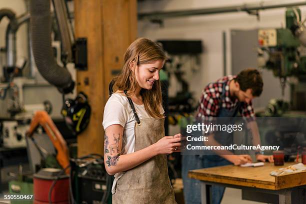 young craftswoman smiling and texting - creative collaboration holding stockfoto's en -beelden