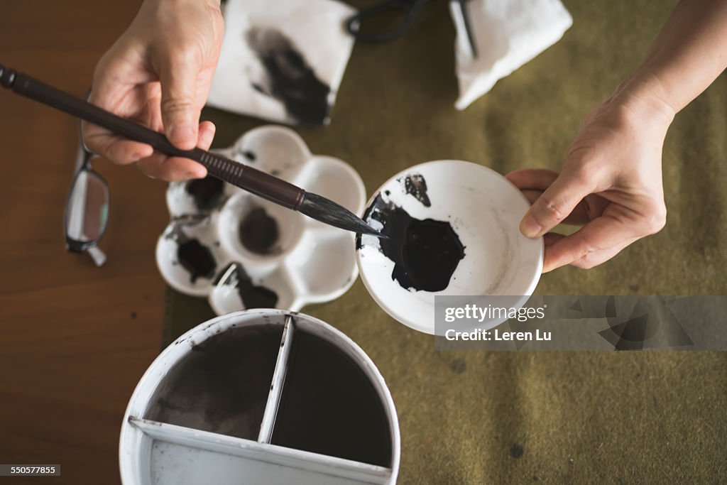 Hand holding writing brush and inking