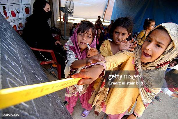 Three young Pashtun refugee girls are reading from a black baord various sentences and words for the rest of the class, June 24th 2009, in Pakistan....