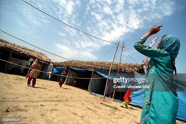 Two Pashtun refugee girls are playing Bagmington in the play yeard near the makeshift classroom, June 24th 2009, in Pakistan. These class rooms where...