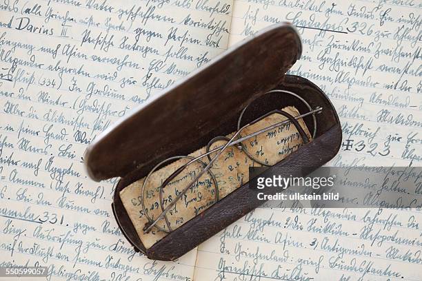 Eine alte Lesebrille in einem Brillenetui auf einem alten Notizbuch
