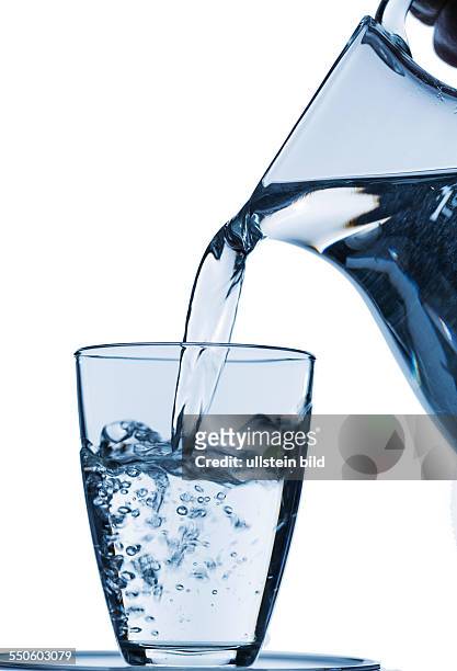 Reines Wasser wird in ein Wasserglas aus einem Krug eingeleert. Frisches Trinkwasser
