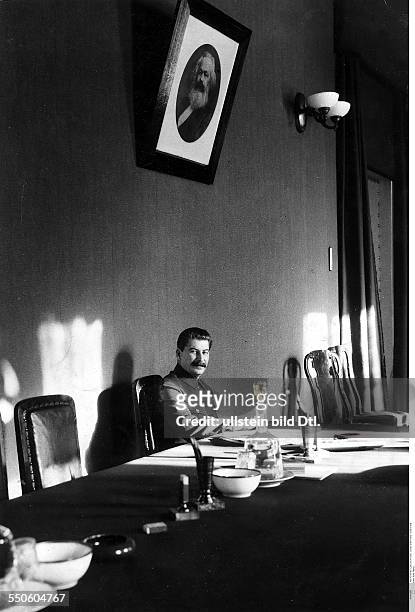 Soviet political leader Joseph Stalin at work in his office, with a portrait of Karl Marx hanging on the wall over his head, 1932. Photographer:...