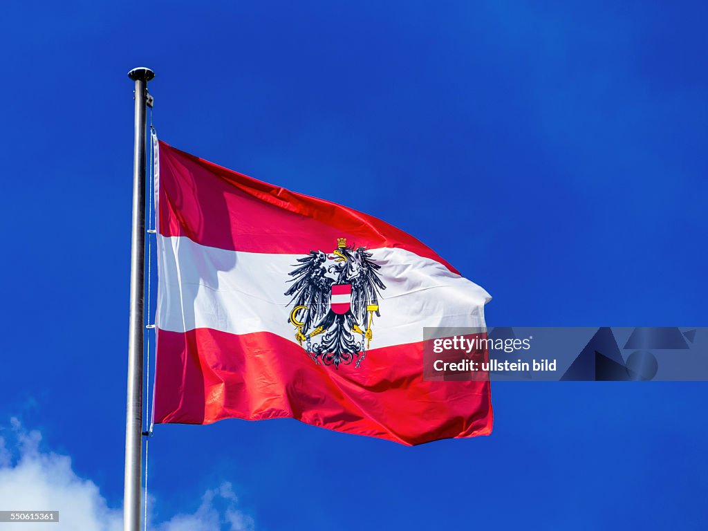 Die österreichische Fahne weht im Wind vor blauem Himmel. Flagge