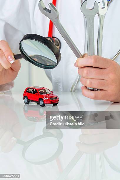 Ein Modell eines Autos wird von einem Arzt untersucht. Symbolfoto für Werkstatt, Service und Autokauf.
