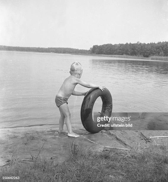 Ca.1950, Ferien auf dem Campingplatz, Kleiner Junge mit Schwimmreifen beim baden