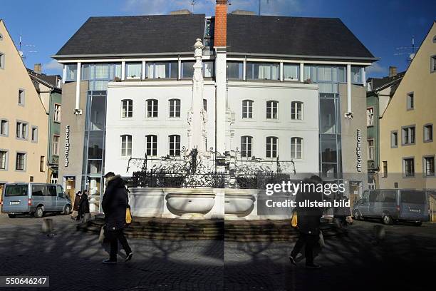 Sonnenschein in Saarbrücken. In einer Plakatwand spiegelt sich der Brunnen auf dem St.Johanner Markt.