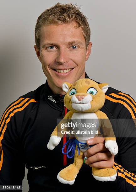 Biathlet Andreas Birnbacher posiert mit einem Maskottchen fuer die Olympischen Winterspiele 2014, waehrend der DSV Saisonpressekonferenz am 30....