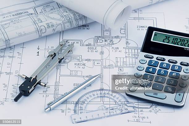 Ein Bauplan eines Architekten mit einem Taschenrechner udn Zirkel. Symbolfoto für Finanzierung und Planung eines neuen Hauses.