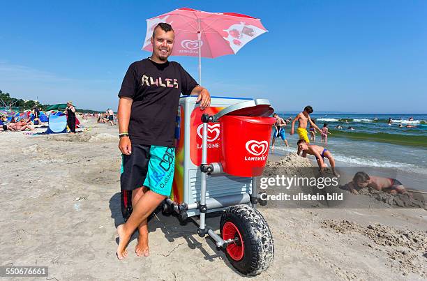 Student Johannes Kloeppel verkauft Eis aus seinem Eiswagen am Ostseestrand.