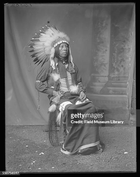 Portrait of Native American Oglala Sioux Edward Bad Hair wearing a feather headdress and holding a feather in his lap at the Louisiana Purchase...
