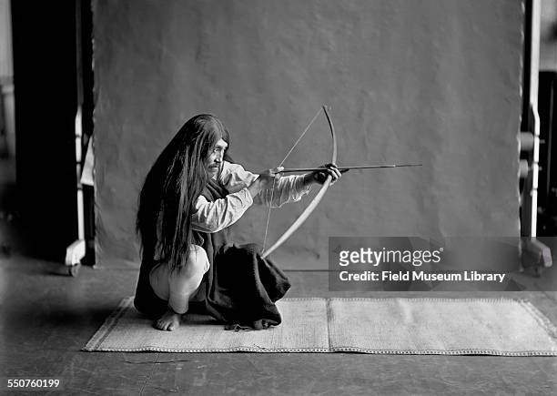 First Nations Kwakiutl man Bob Harris, wearing a long hair wig, shooting a bow and arrow at the Louisiana Purchase Exposition, St Louis, Missouri,...