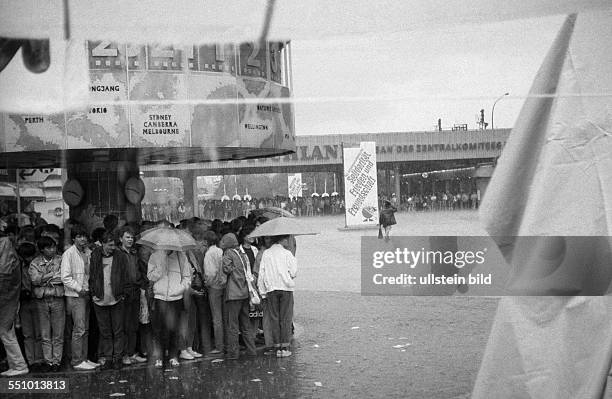 Passanten flüchten vor einem Regenguss unter die Weltzeituhr auf dem Ostberliner Alexanderplatz am Rande des Pfingsttreffen der FDJ in Ost-Berlin