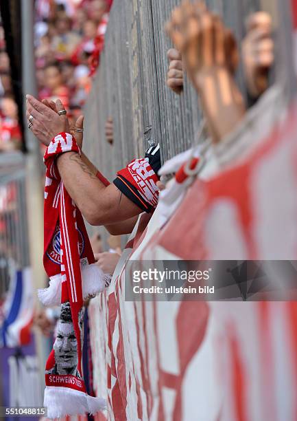 Ein Fan mit einem Bastian Schweinsteiger Fanschal streckt die Arme durch die Stangen und klatsch waehrend dem Fussball Bundesliga Spiel FC Bayern...