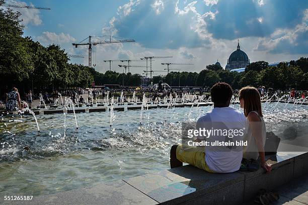 Berliner suchen Abkühlung an den Springbrunnenbecken auf dem Alexanderplatz in Berlin