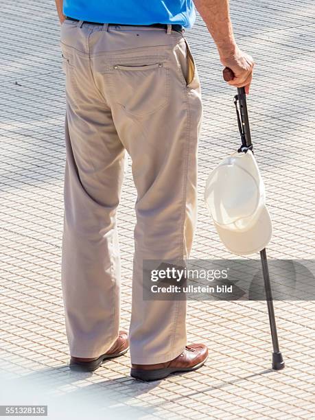 Ein Tourist mit einem geshtock und einer Kappe als Sonnenschutz