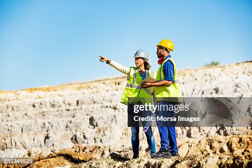 Architect explaining plan to quarry worker at site Architect explaining plan to quarry worker at site