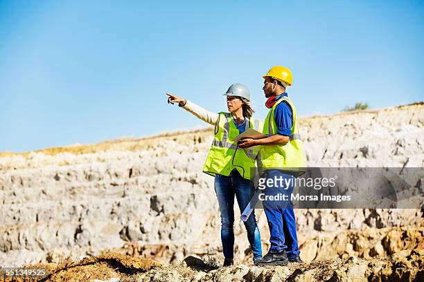 architect explaining plan to quarry worker at site - mining natural resources stock pictures, royalty-free photos & images